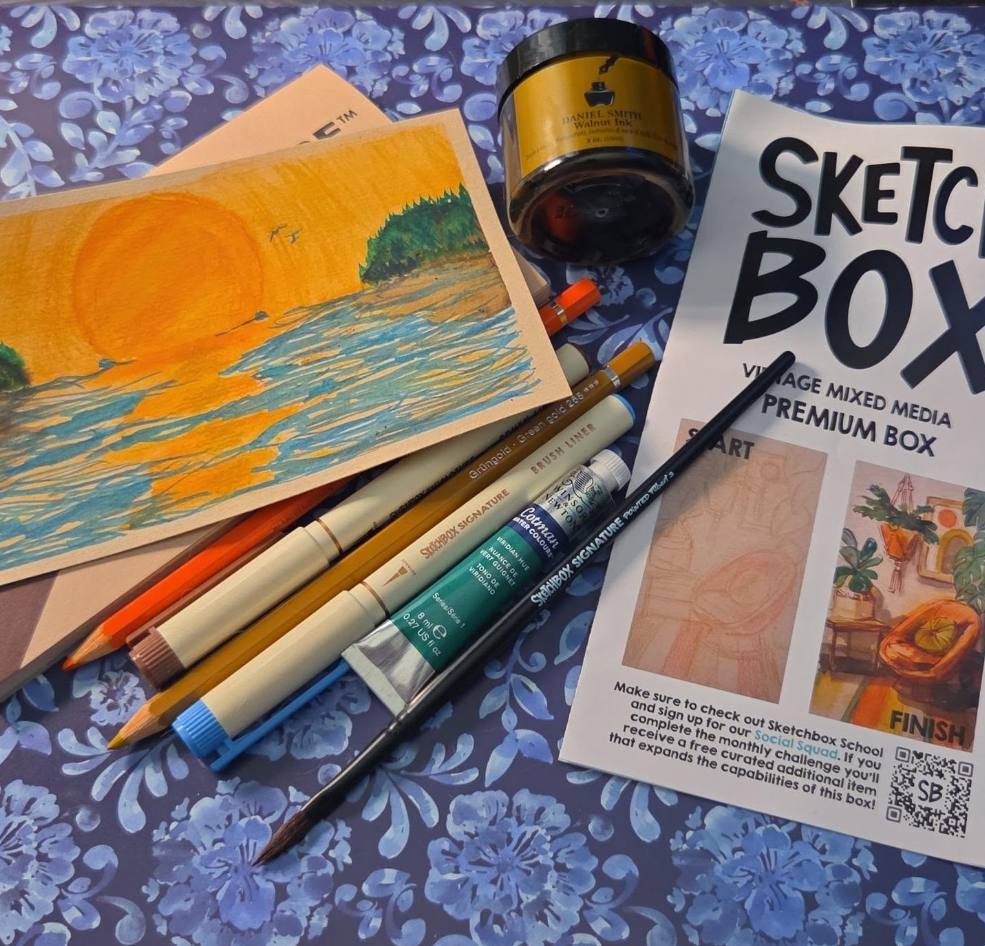 September SketchBox mixed-media beach painting with a large orange sunset, blue ocean, green trees, and golden reflections.